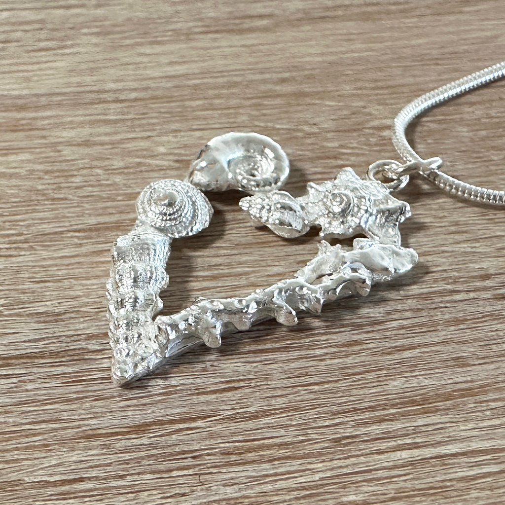 Heart shaped fine silver pendant with little handcart shells in silver