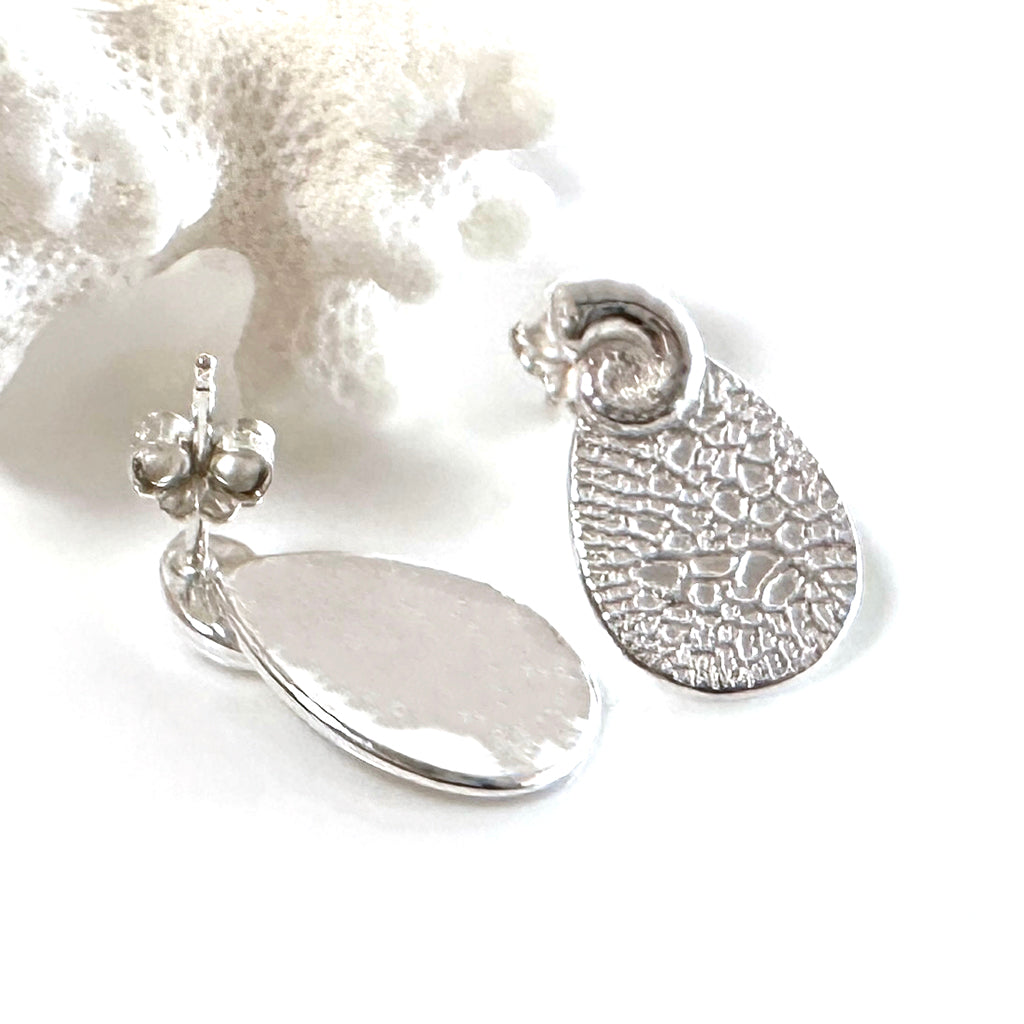 Handcrafted Reef Reflections stud earrings  inspired by Australian coral formations and marine ecosystems. Ethical ocean-inspired designs by Coastalstyle Australia displayed against a soft pink sea urchin shell.