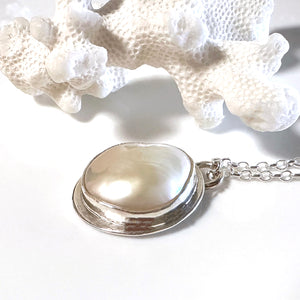 Handcrafted Silver Sands Pearl Necklace showcasing lustrous Australian pearl set in textured recycled silver with sand-inspired finish. Elegant ocean jewelry by Coastalstyle Australia displayed on neutral background near a piece of white coral