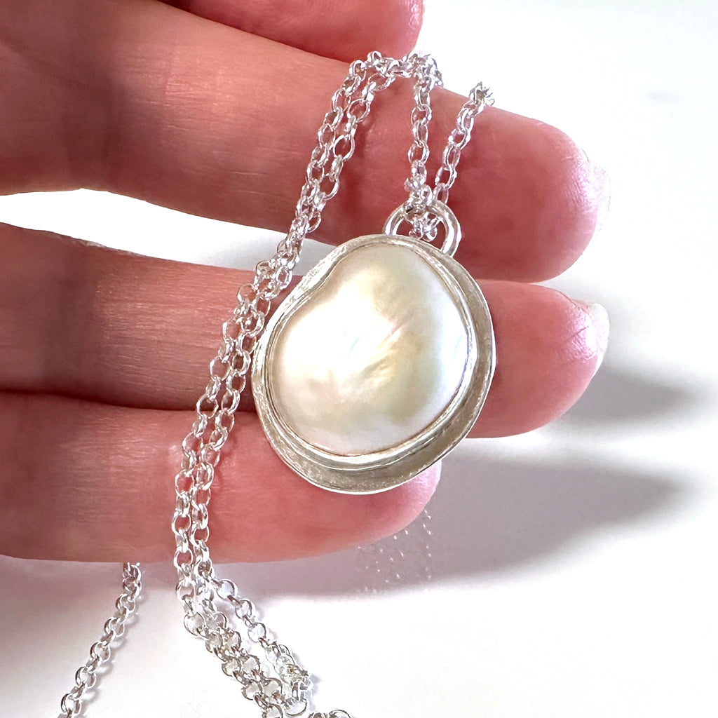 Handcrafted Silver Sands Pearl Necklace showcasing lustrous Australian pearl set in textured recycled silver with sand-inspired finish. Elegant ocean jewelry by Coastalstyle Australia displayed on a hand