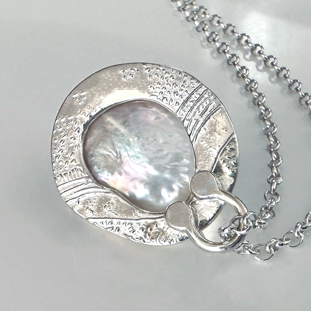 Handcrafted Silver Sands Pearl Necklace showcasing lustrous Australian pearl set in textured recycled silver with sand-inspired finish. Elegant ocean jewelry by Coastalstyle Australia displayed on a nautilus shell