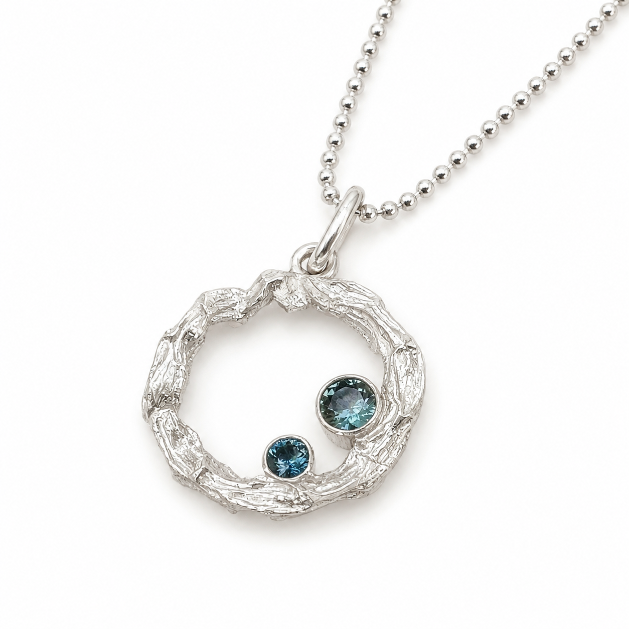 Pure silver Sapphire Reef Necklace on white background — open circle coral reef pendant with two bezel-set teal sapphires in different sizes on a silver ball chain. Ocean-inspired jewellery by Coastalstyle Australia"