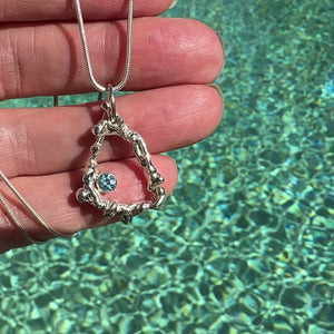 Handcrafted Argentium silver coral pendant featuring intricate branch-like texture with blue topaz gemstone, displayed on hand and sparkling ocean  background. Ocean-inspired ethical jewelry by Coastalstyle Australia