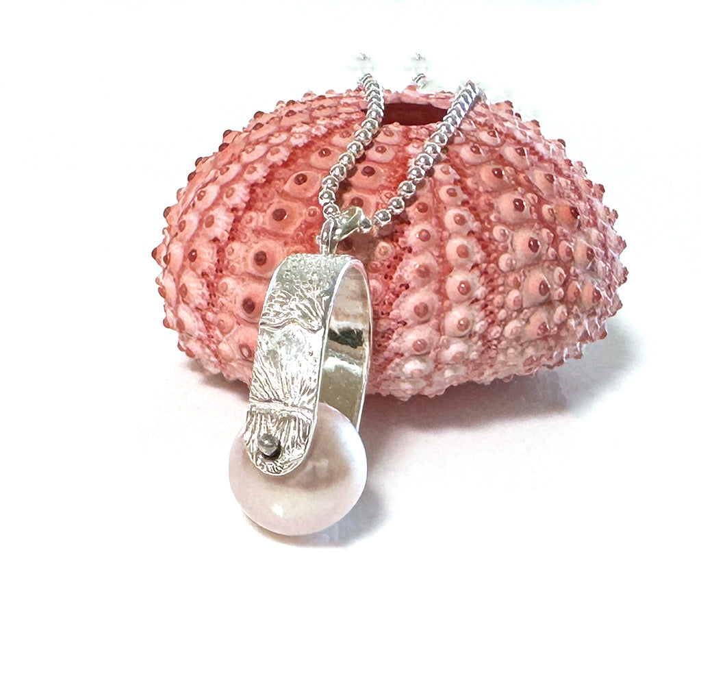 Moving sands spinner pearl close up with soft shell pink pearl on piece of coral. Coastalstyle Australia.