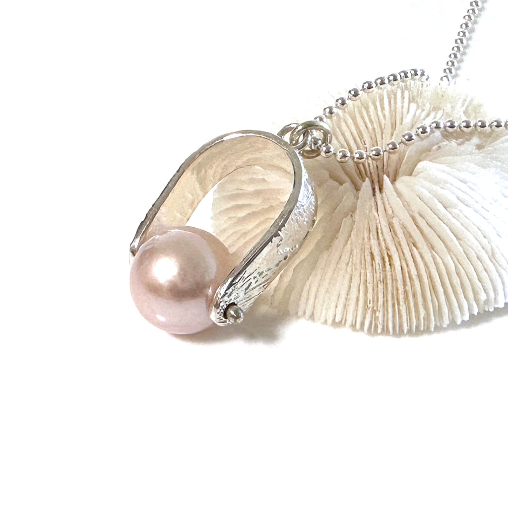 Moving sands spinner pearl close up with soft shell pink pearl on piece of coral. Coastalstyle Australia.